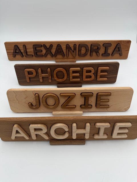 Four finished single-row puzzles reading ALEXANDRIA, PHOEBE, JOZIE and ARCHIE, displayed on separate stands
